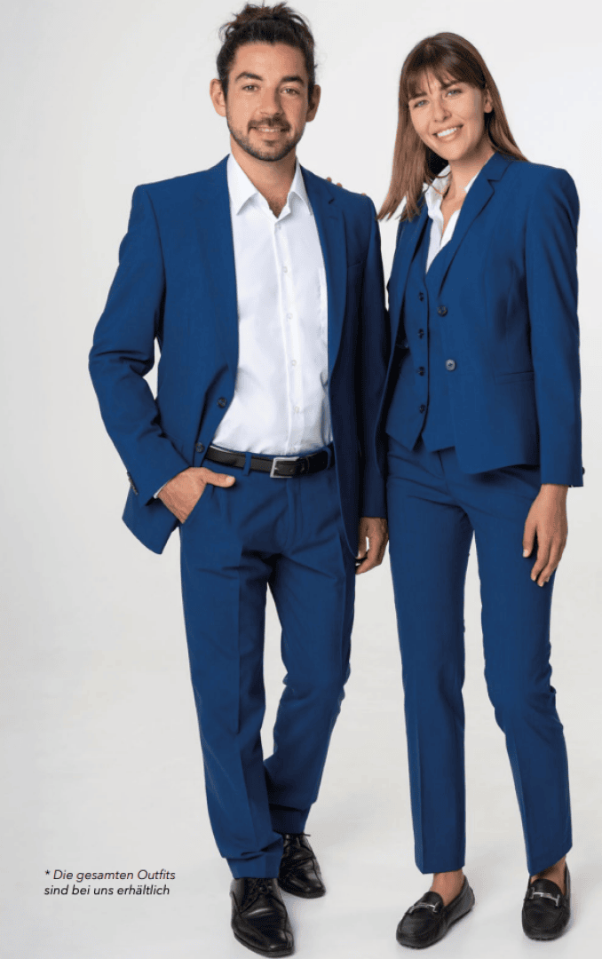 Zwei Personen stehen nebeneinander. Beide tragen passende blaue Anzüge und weiße Hemden. Die Person links trägt einen Anzug ohne Krawatte, die Person rechts einen Hosenanzug mit Weste. Beide lächeln in die Kamera.