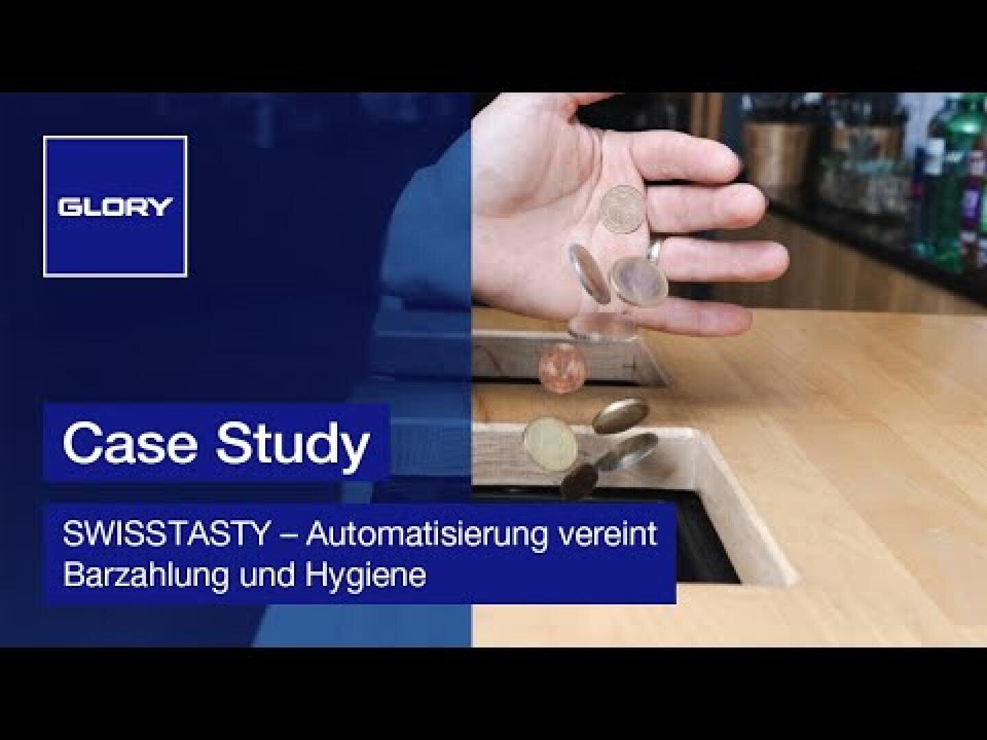 Eine Person wirft Münzen in einen Schlitz auf einem Holztresen. Das Bild enthält ein blaues Overlay mit dem Text Case Study und SWISSTASTY - Automatisierung vereint Barzahlung und Hygiene. In der Ecke erscheint das GLORY-Logo.