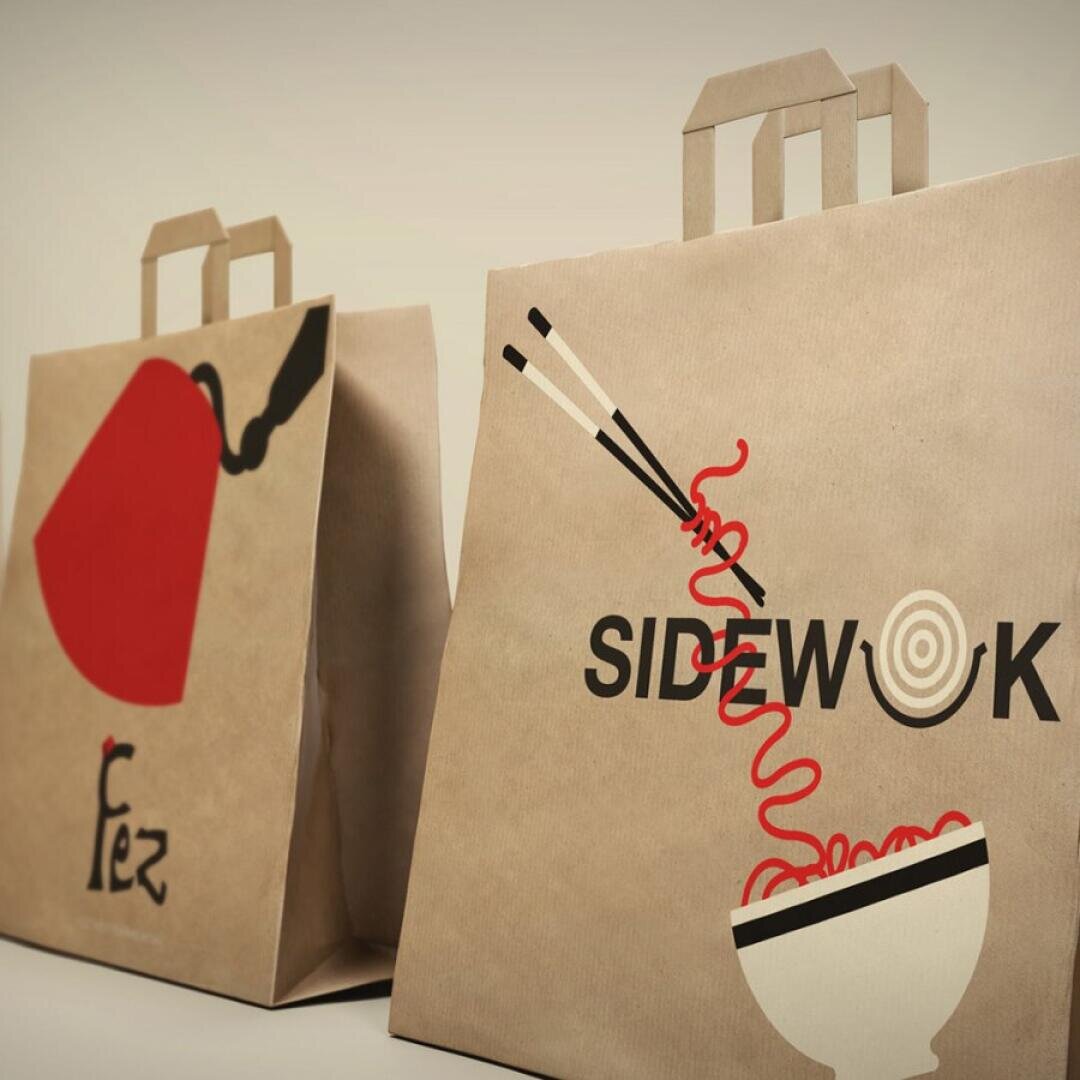 Deux sacs en papier brun à emporter avec des motifs créatifs : l'un représente une théière rouge et le mot Fez, l'autre des baguettes tenant des nouilles au-dessus d'un bol avec le mot SIDEWOK.