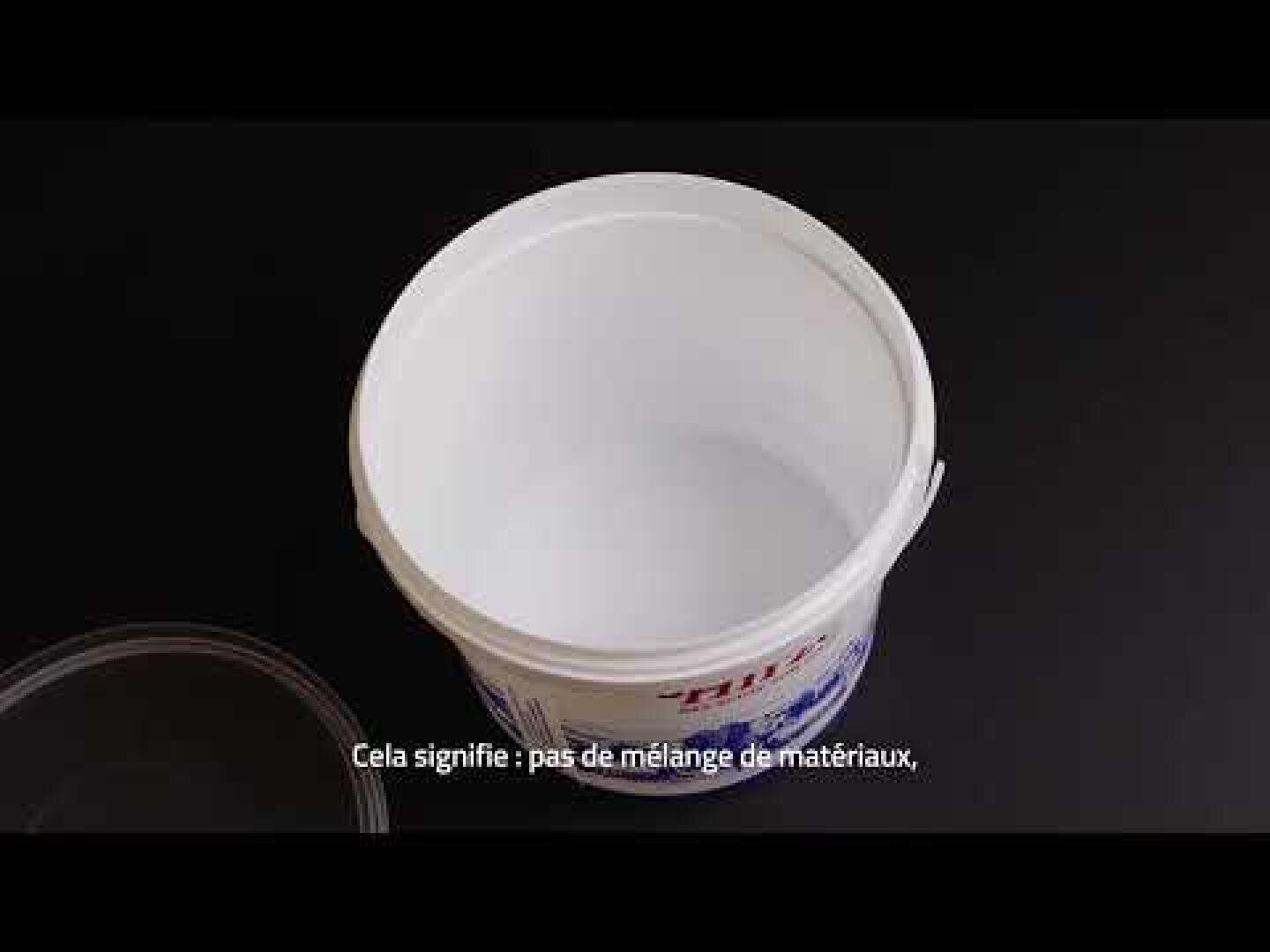 Un récipient en plastique blanc vide avec un couvercle sur une surface noire. Le texte en français sur le fond dit : Cela signifie : pas de mélange de matériaux.
