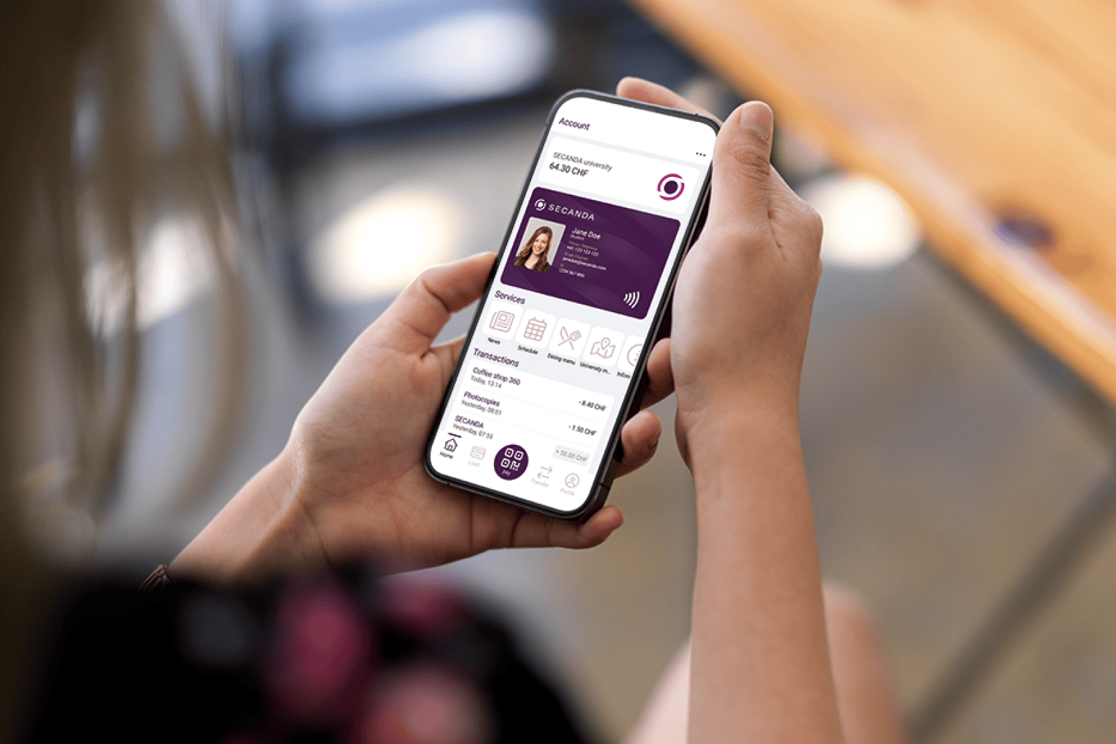 Eine Person hält ein Smartphone, auf dessen Bildschirm eine digitale Banking-App mit Kontodetails, Transaktionsverlauf und einer virtuellen Kartenschnittstelle angezeigt wird.